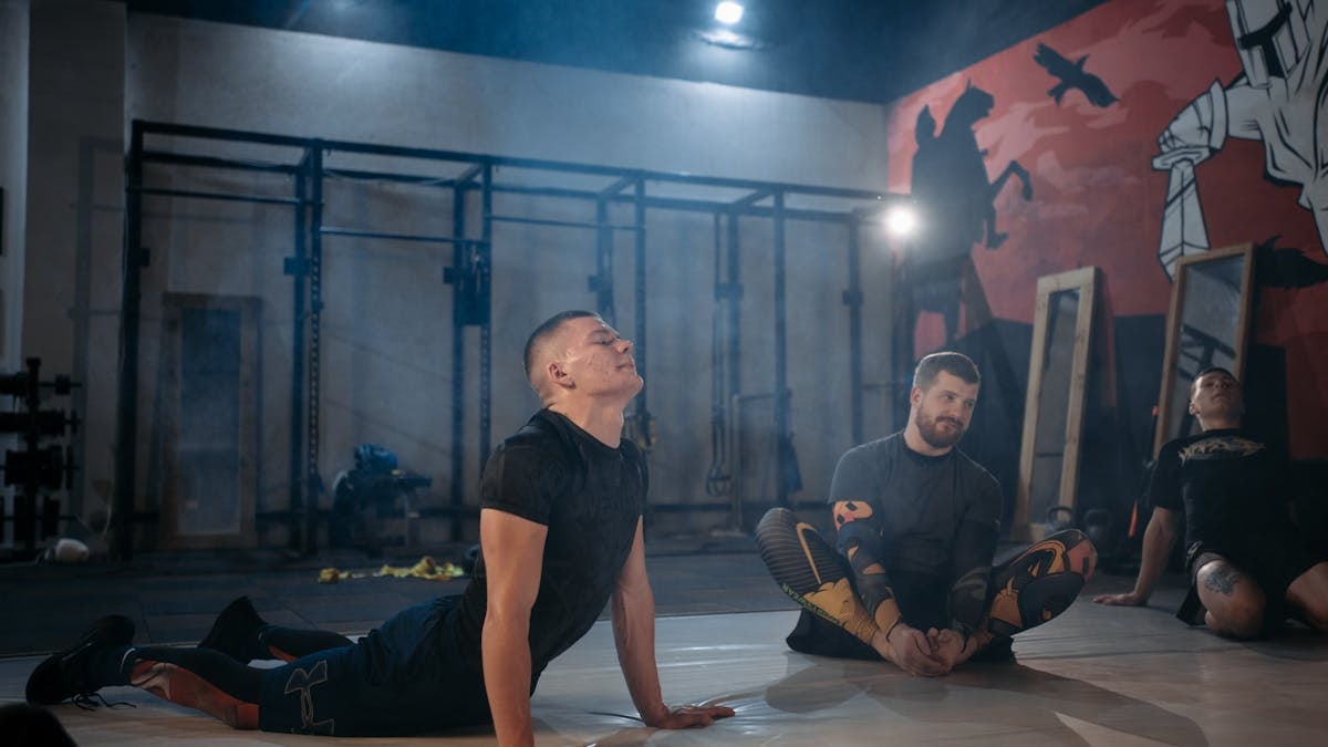 Men participating in a fitness class, stretching and exercising together indoors.